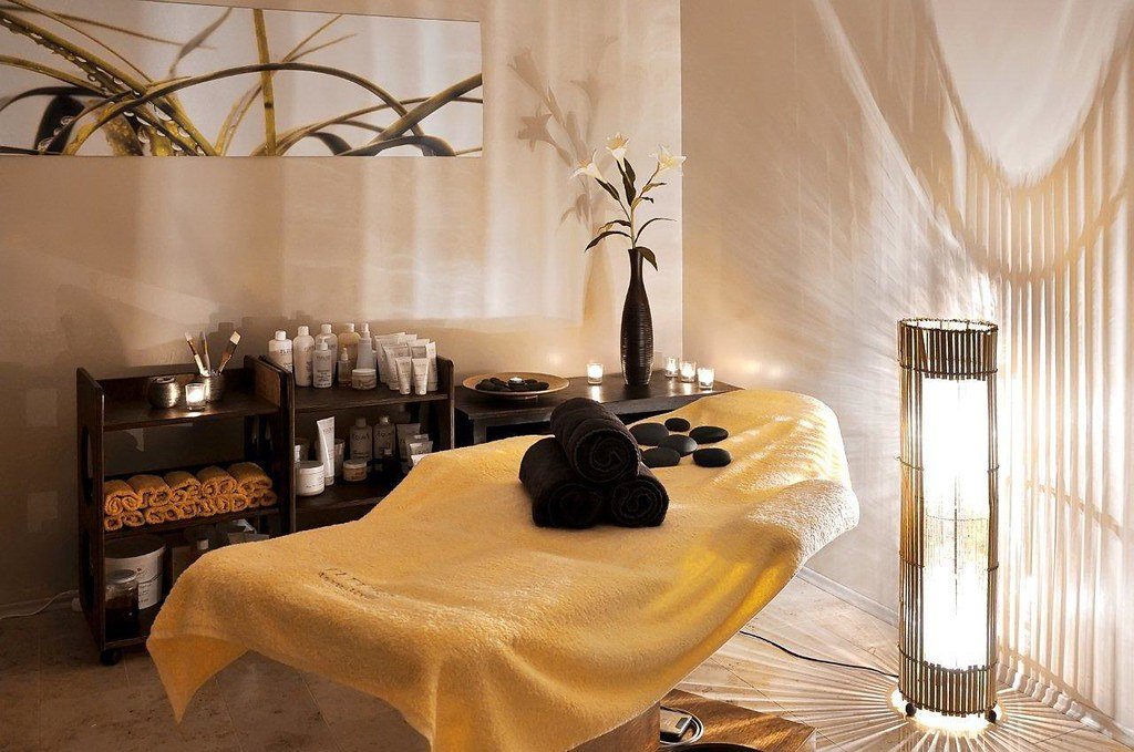 Sala de spa con camilla, velas y toallas